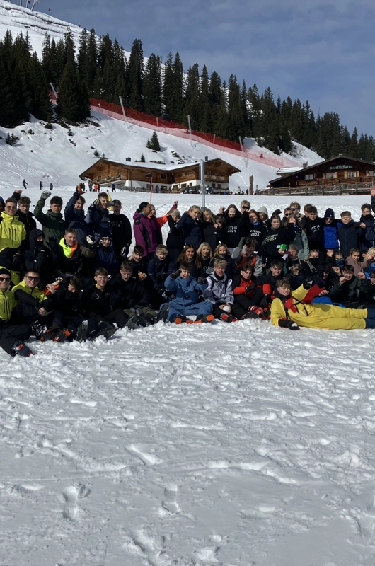 Masse unge der står på en ski bakke og smiler til kameraet